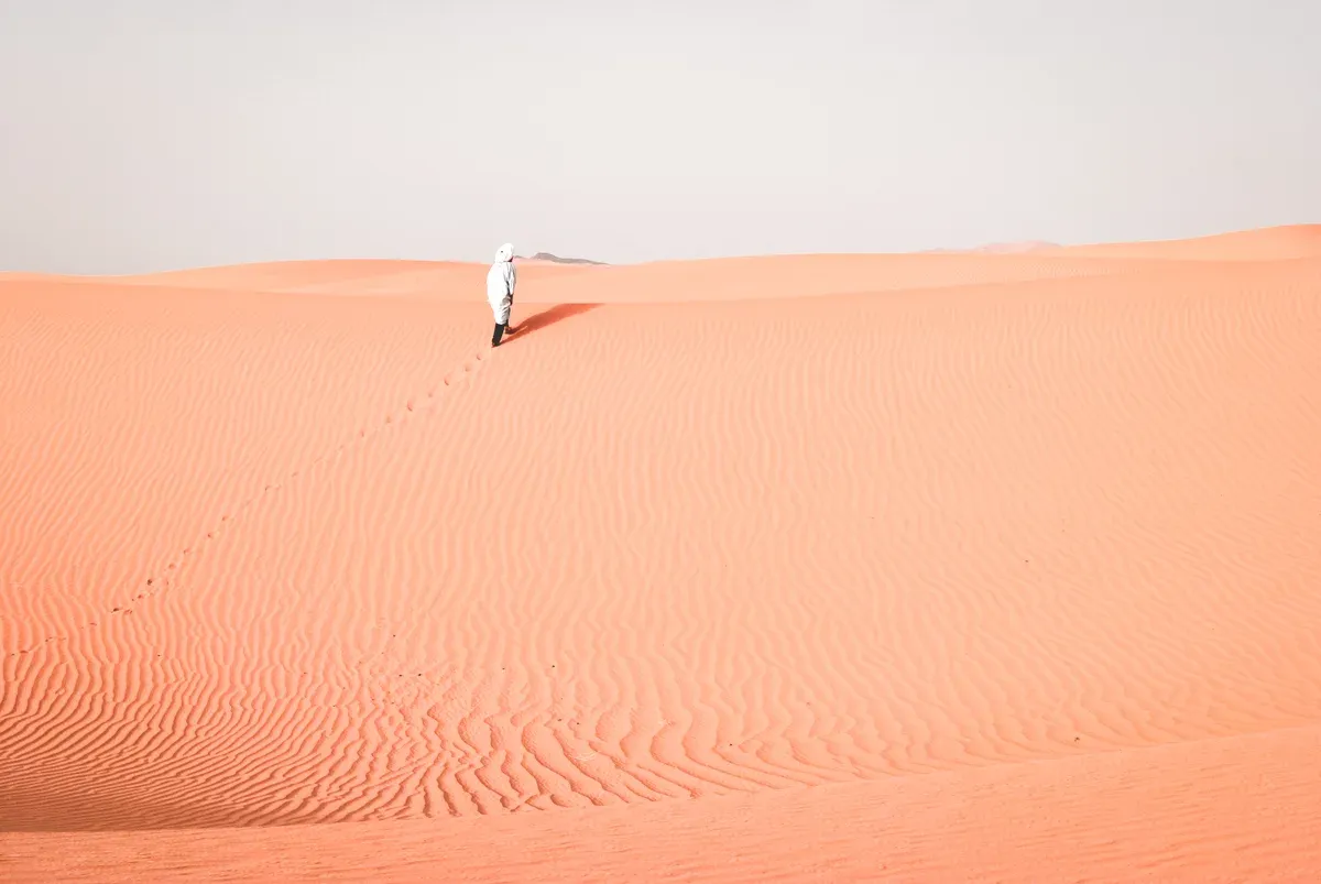 A traveller walking a ridge of orange sand in the Erg Chebbi dunes near Merzouga, the desert night on Morocco tour packages