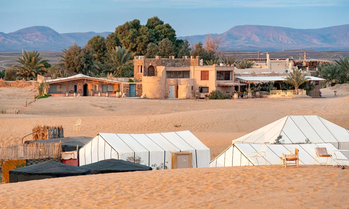 White tents of a desert camp at the foot of the Erg Chebbi dunes on a Morocco tour package, Erg Chebbi desert camp, Merzouga, Morocco
