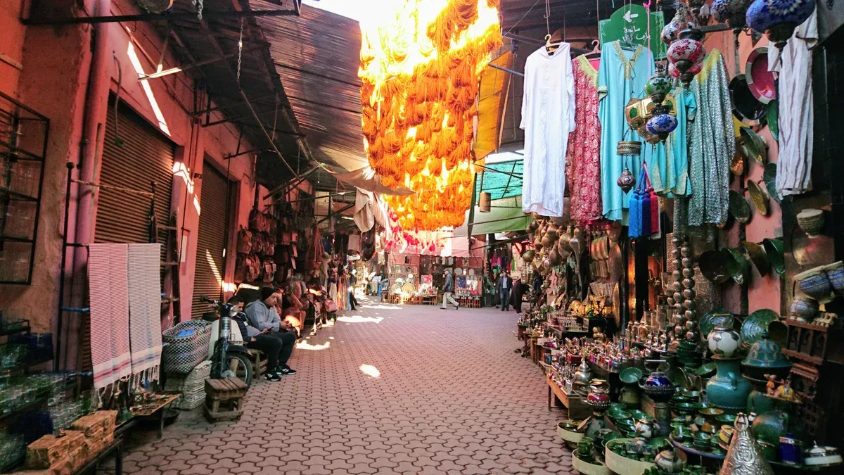 A souk lane lined with leather, textiles and ceramics in the Marrakech medina on a Morocco tour package, Marrakech medina souk, Morocco